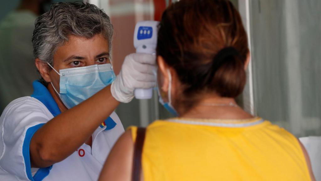 Una trabajadora de Sanidad toma la temperatura a las personas que esperan en las urgencias .