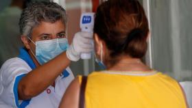 Una trabajadora de Sanidad toma la temperatura a las personas que esperan en las urgencias .