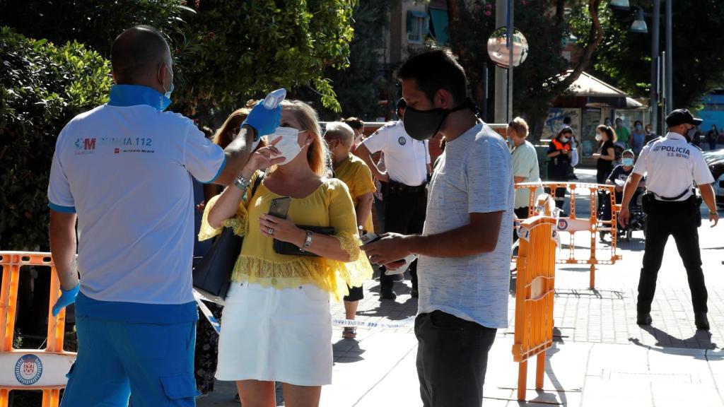 Un paramédico toma la temperatura a un mujer antes de acceder al centro de salud Reyes Católicos.