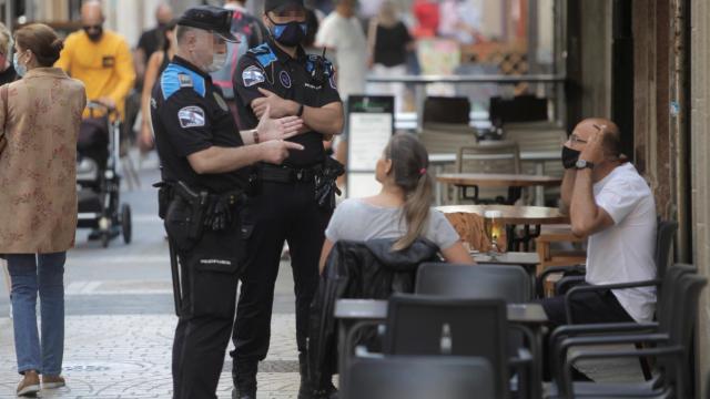 Dos agentes de la policía local de A Coruña se dirigen a un hombre que fumaba en una terraza.