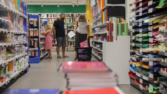 Una pareja acompañada por una niña realiza una compra de material escolar en Valencia.