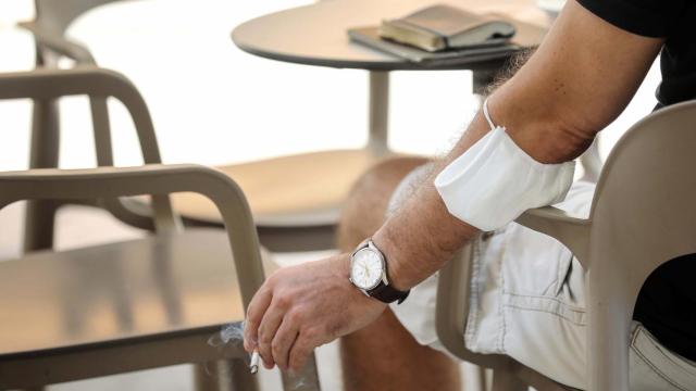 Un hombre fuma un cigarro en una terraza.