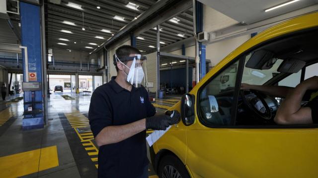 Un trabajador de una estación de ITV  de Madrid da las indicaciones desde fuera del coche a un conductora.