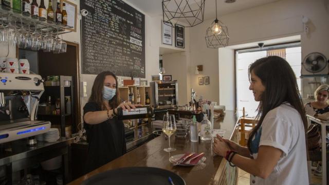 Una camarera sirve una copa de vino a una clienta.