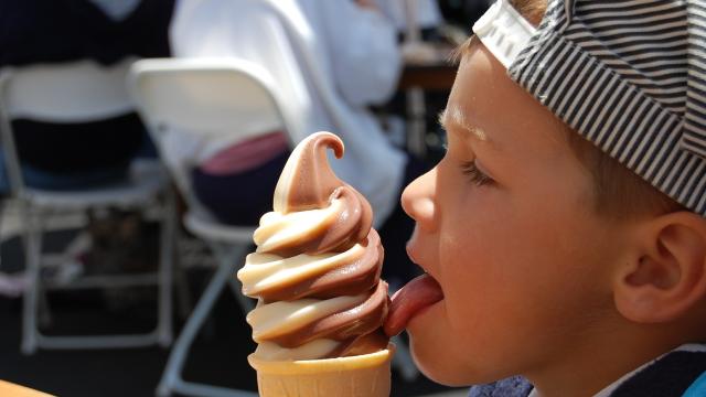 Un niño lamiendo un helado.