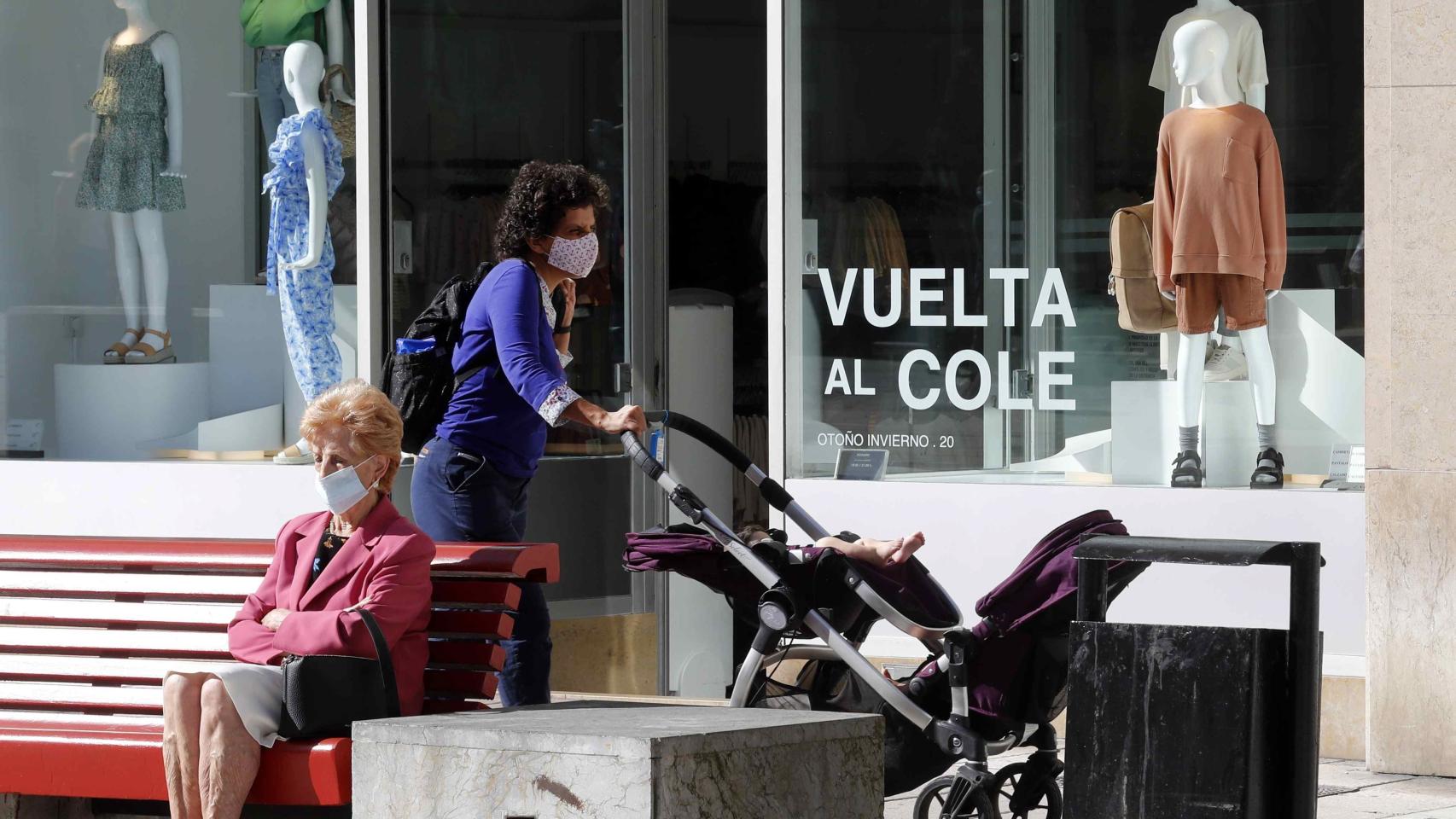 Una mujer camina frente a un escaparate con la campaña de la vuelta al colegio en una calle del centro de Oviedo.