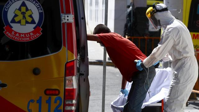 Un trabajador de Hospital 12 de Octubre equipado frente a la Covid ayuda a un paciente.