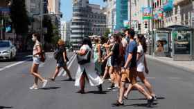 Un grupo de gente cruza la Gran Vía de Madrid con mascarillas.