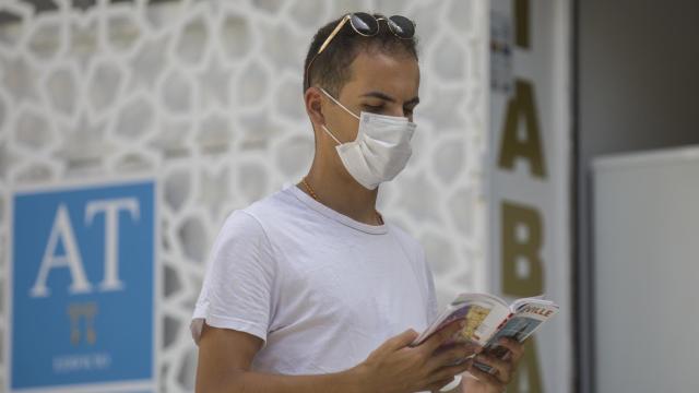 Un turista lee una guía mientras pasea por el casco histórico de Sevilla.