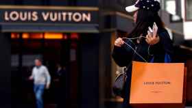 FILE PHOTO: Woman with a Louis Vuitton-branded shopping bag looks towards the entrance of a branch store by LVMH Moet Hennessy Louis Vuitton in Vienna