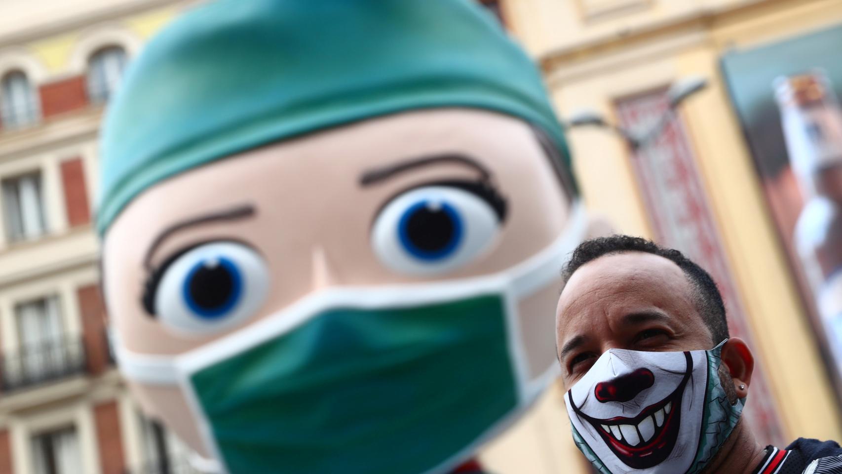 Una persona con una mascarilla decorada junto a la figura del 'súper sanitaria' de Callao. Reuters/Sergio Pérez