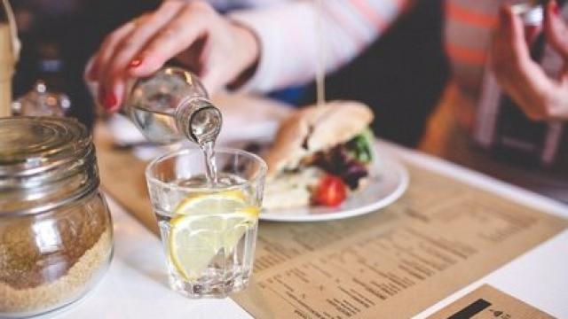 Una persona se echa agua en un restaurante.