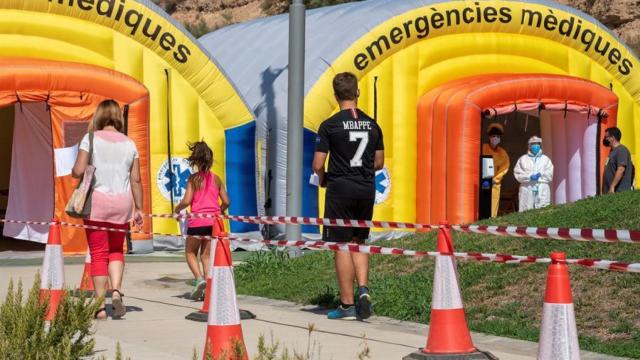 Vecinos de Alcarràs (Lérida) hacen cola para ser atendidos por profesionales sanitarios en una instalación móvil.