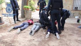 Los tres detenidos, en el suelo y custodiados por la Policía Nacional