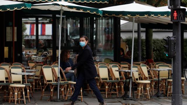 Una mujer camina al lado de una terraza vacía.