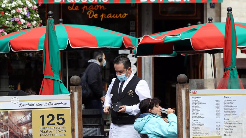 Un camarero con mascarilla trabajando en un restaurante de la Grand Place de Bruselas.