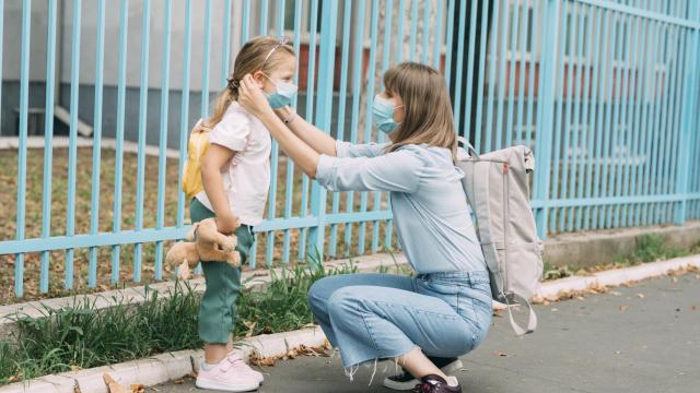 Una madre, agachada, atiende a su hija.