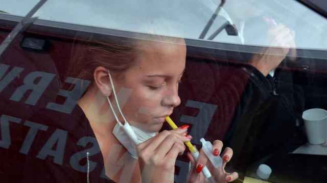 Una joven realiza un test de gárgaras desde su coche para detectar la Covid-19.