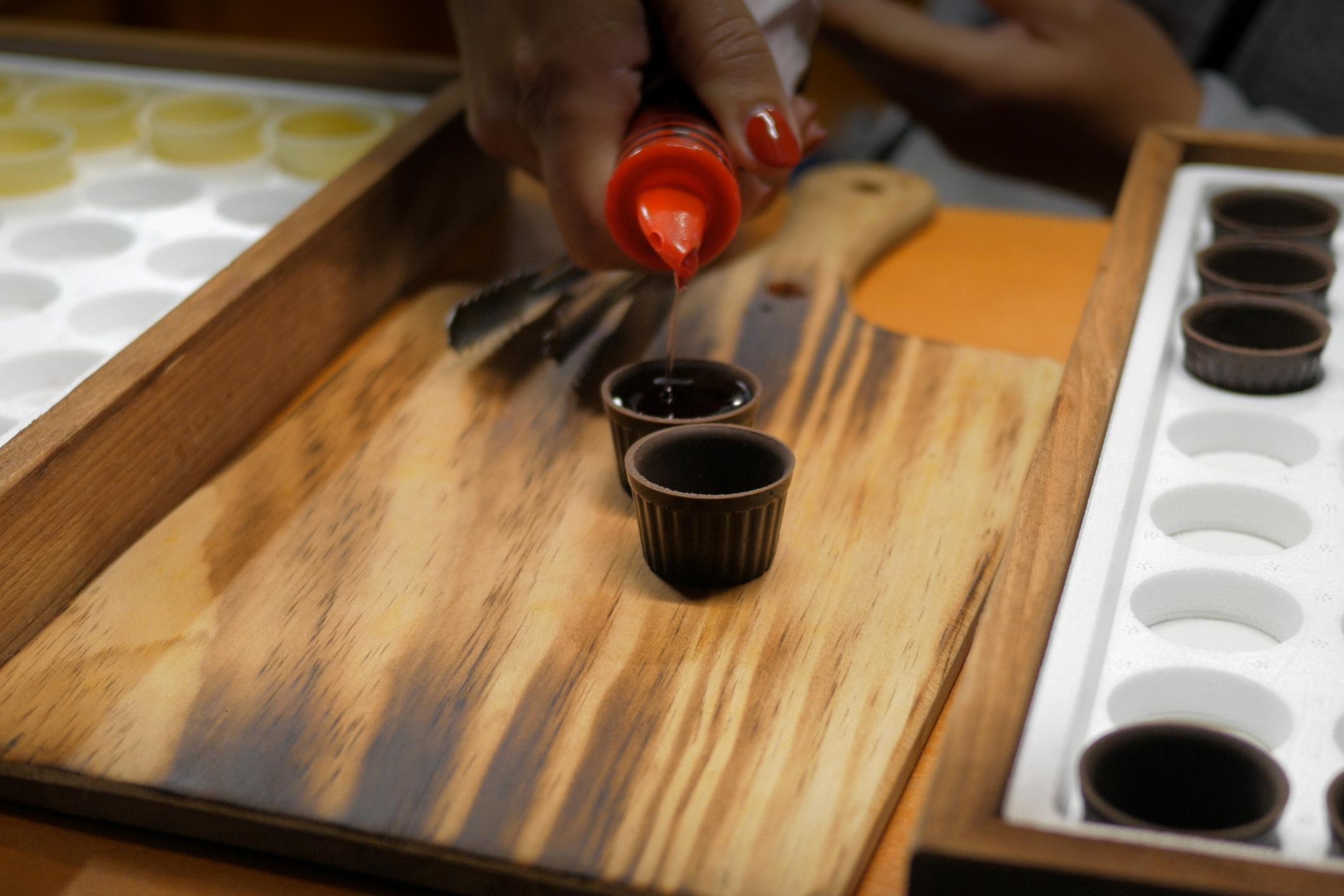 Una persona sirve Ginjinha en vasos de chupito de chocolate.