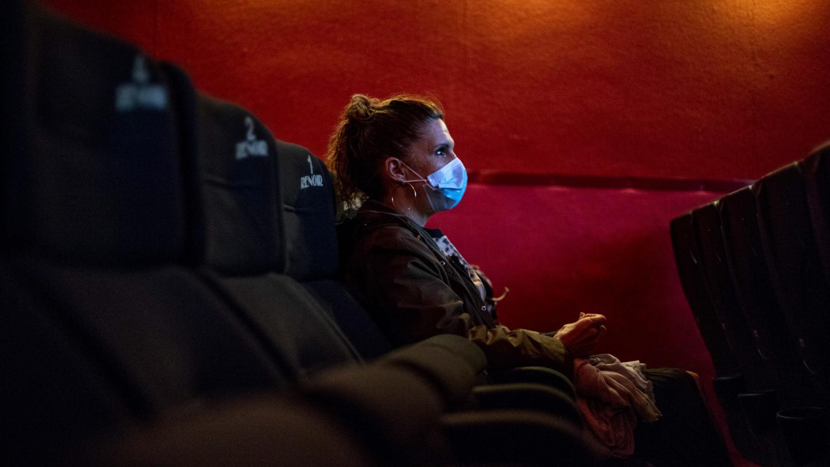 Una mujer acude a una proyección con mascarilla.