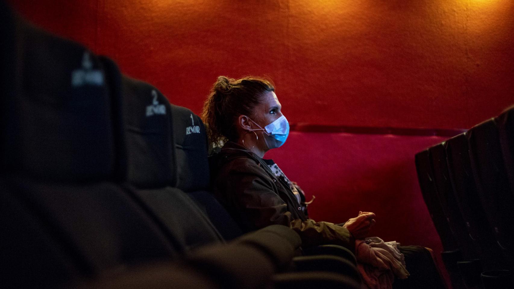 Una mujer acude a una proyección con mascarilla.