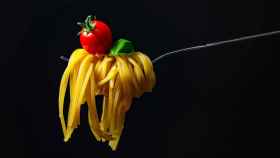 Un tenedor cargado de espaguetis (integrales) y con un tomate.