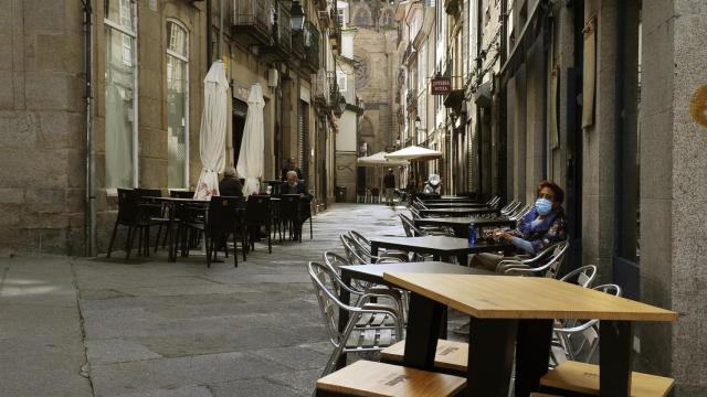 Una mujer permanece sentada en una terraza del barrio de O Couto, en Ourense.