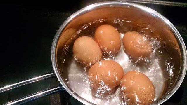 Un cazo con unos huevos cociéndose en su interior.