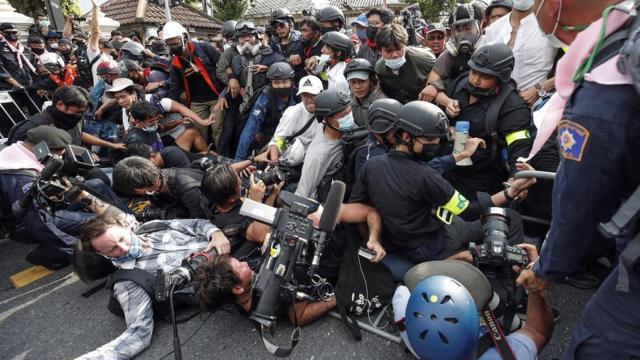 Manifestantes y periodistas caen al suelo durante una manifestación.