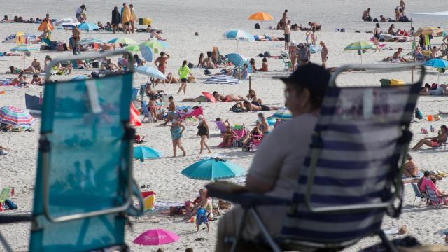 Una persona sentada frente a la playa en A Mariña.