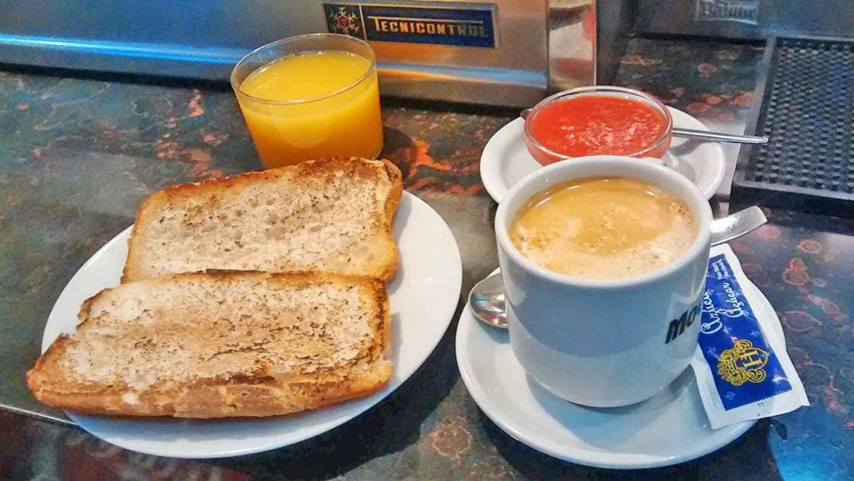 Un desayuno clásico con tostadas, café y zumo de naranja.