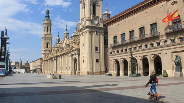 Una mujer pasea a su perro en la plaza del Pilar en Zaragoza.