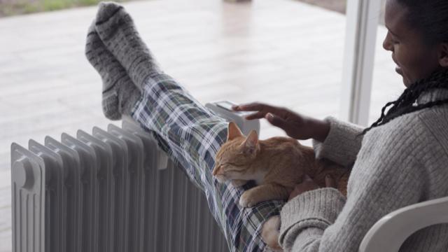 Una mujer y su gato apoyada en un radiador.