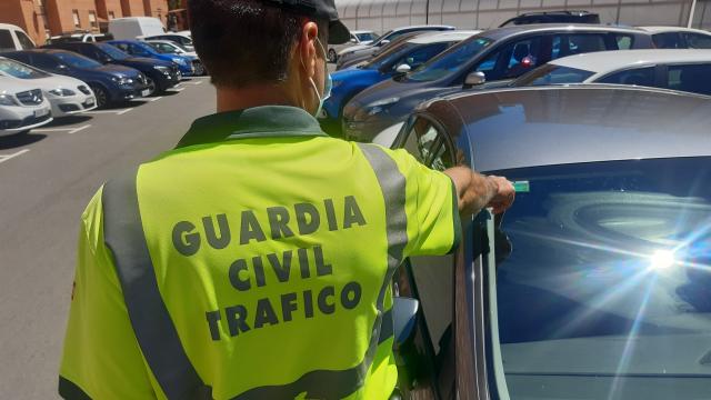 Un agente de la Guardia Civil comprobando si la pegatina de la ITV de un coche está vigente.