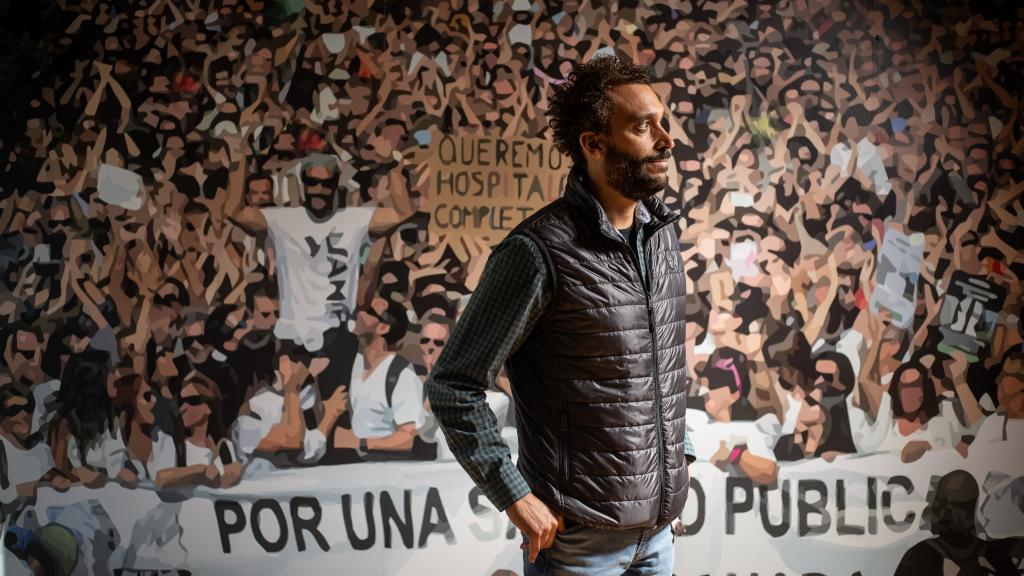 El médico granadino Jesús Candel, más conocido como Spiriman, ante un vinilo con una imagen de las manifestaciones multitudinarias que organizó contra la gestión de la sanidad pública andaluza.
