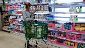 Una consumidora, en un supermercado, eligiendo un producto para su cesta de la compra.
