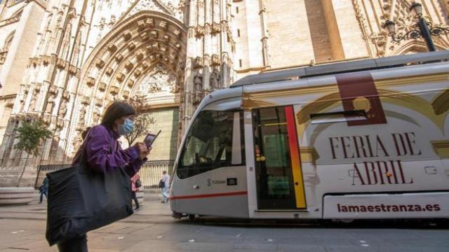 Una mujer con mascarilla pasea por delante de la Catedral de Sevilla.