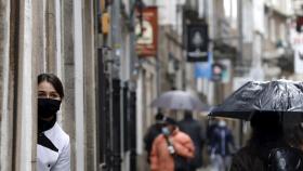 Una empleada de un local en una calle turística observa a los turistas en Santiago de Compostela.