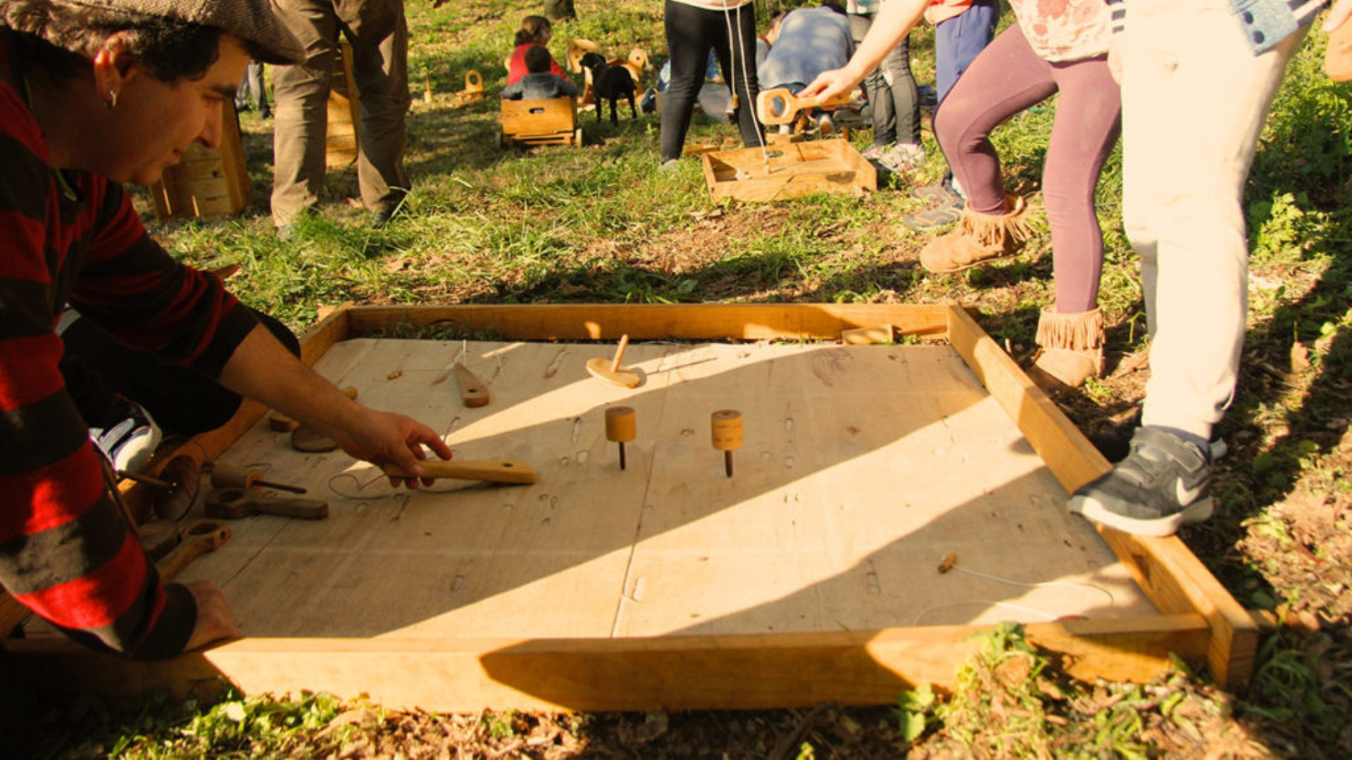 César juega con los niños a un juego tradicional fabricado en madera