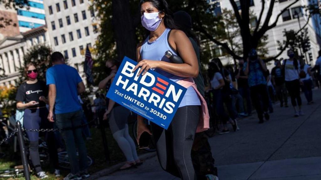 Una mujer sostiene el cartel de Biden.