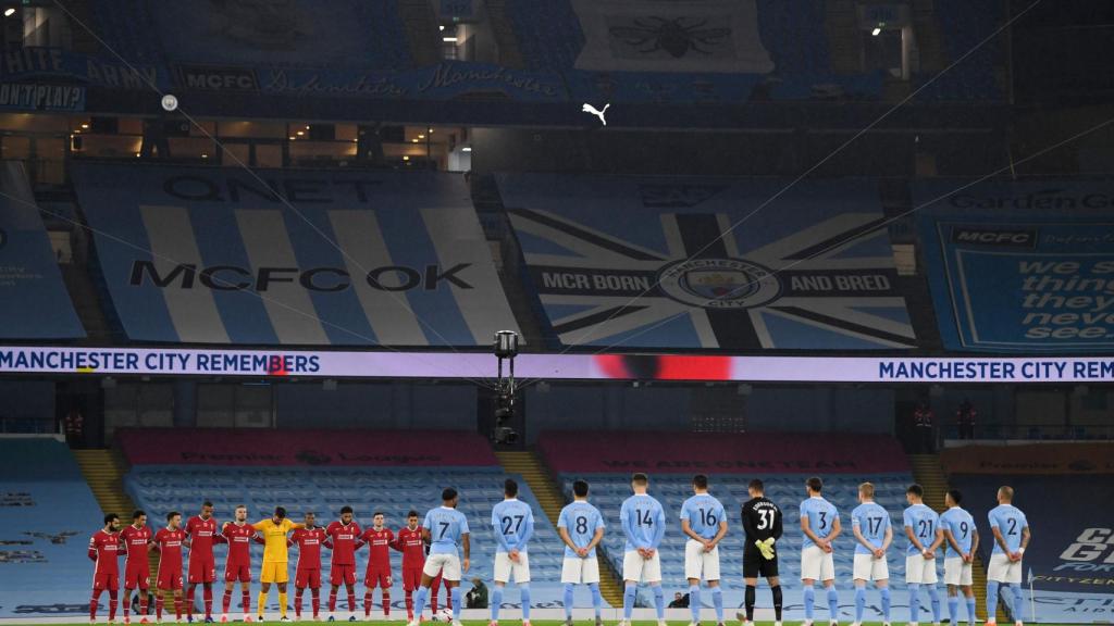 Los jugadores de Liverpool y Manchester City, durante un minuto de silencio en el Etihad Stadium con las gradas vacías