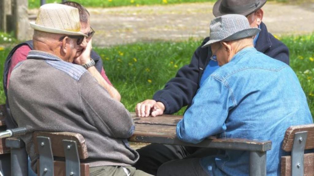 Varios jubilados conversan en un parque