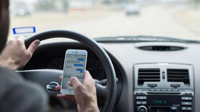 Un conductor utilizando su teléfono en el interior del coche.