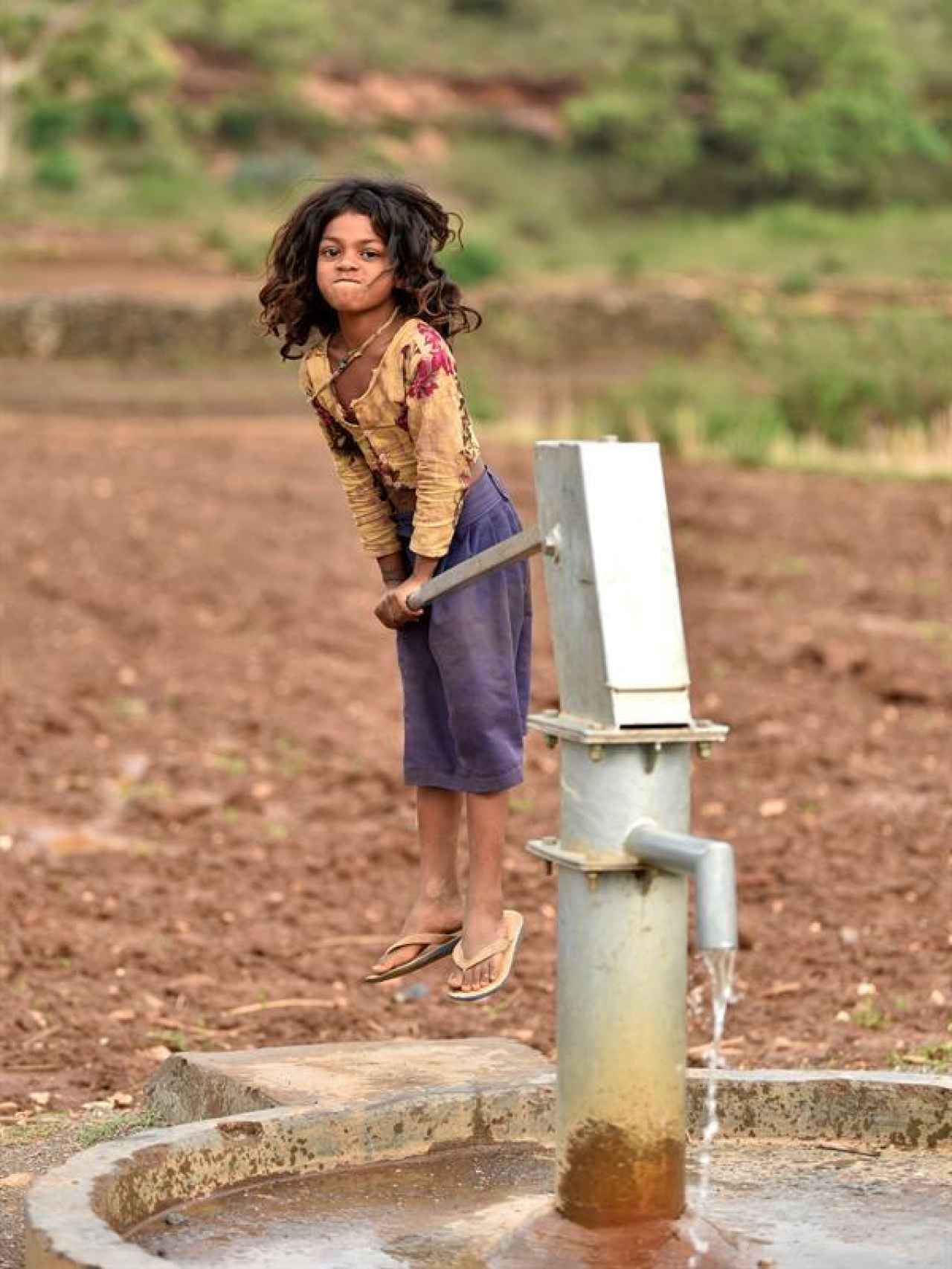 Una niña saca agua de un pozo.