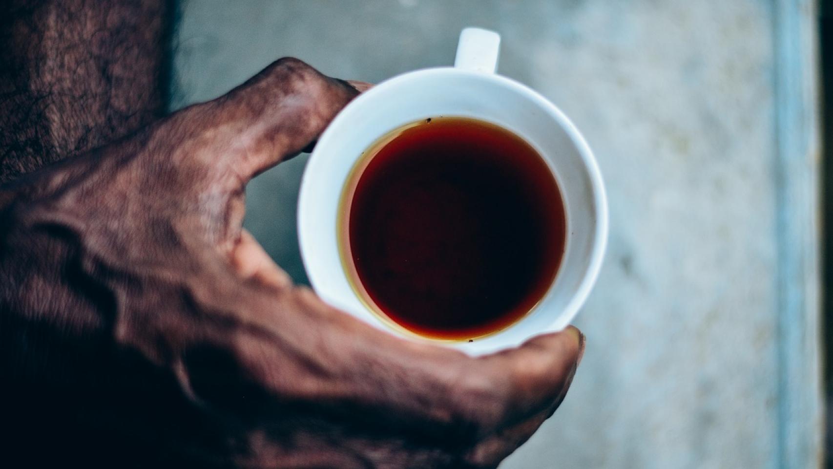 Un hombre sujetando una taza de té rojo.