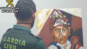 Agente de la Guardia Civil con un cuadro atribuido falsamente a un pintor gallego.