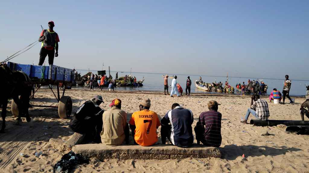 Un grupo de hombres observa a los pescadores en una playa de Joal-Fadiouth.