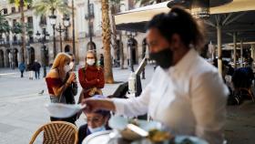 Una mujer atiende una terraza en Barcelona.