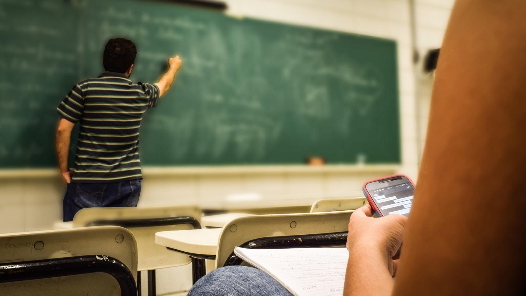 Un alumno consulta el móvil durante una clase.