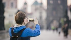 Una turista fotografía el Puente de Carlos en Praga con su smartphone.